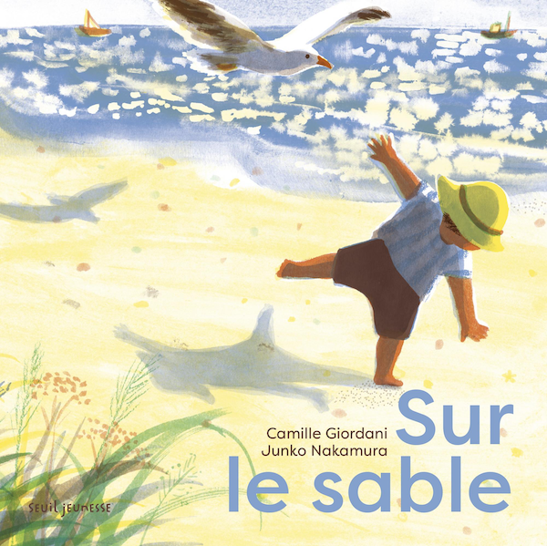 Couverture de l’album Sur le sable : un tout-petit au chapeau jaune joue sur une plage ensoleillée, une mouette vole au-dessus de la mer.